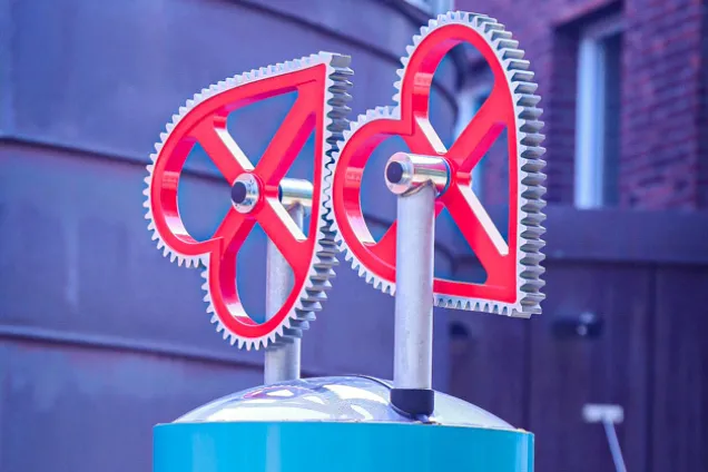 Två mekaniska hjärtan hakar i varandra som kugghjul. Foto.